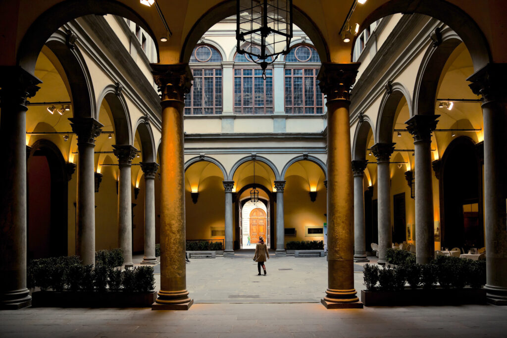 Vue d'une cour avec des arcs et une personne marchant dans le Palazzo Medici Riccardi à Florence.